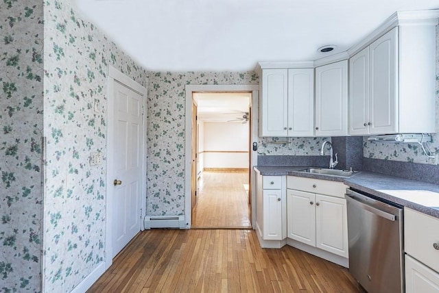 kitchen featuring baseboard heating, white cabinetry, a sink, dishwasher, and wallpapered walls