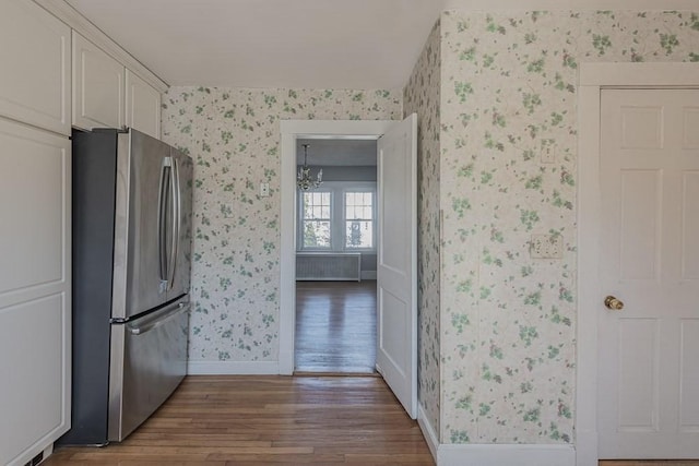 kitchen featuring wallpapered walls, baseboards, white cabinets, dark wood-style flooring, and freestanding refrigerator