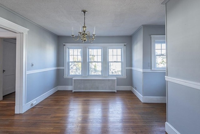 unfurnished dining area featuring ornamental molding, radiator, a chandelier, and wood finished floors