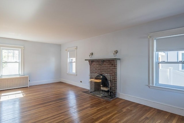 unfurnished living room with radiator heating unit, baseboards, and wood-type flooring