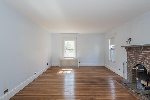 unfurnished living room featuring radiator heating unit, a fireplace, wood finished floors, and baseboards