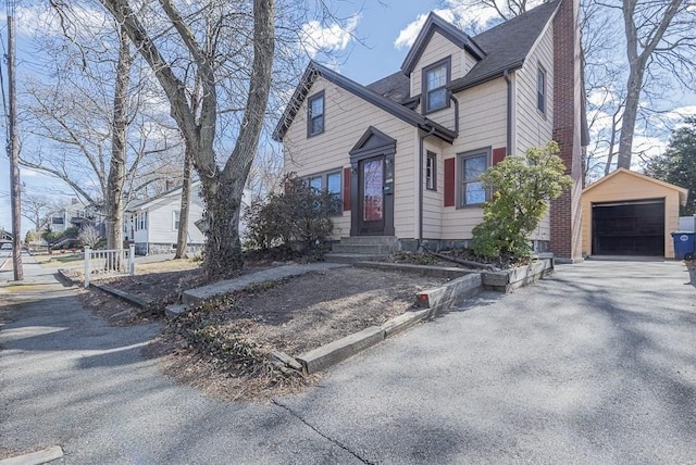 view of front of home featuring a chimney, a shingled roof, entry steps, a garage, and an outdoor structure