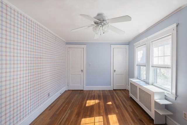 spare room with wallpapered walls, baseboards, radiator heating unit, ornamental molding, and wood finished floors