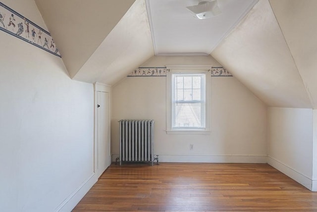 bonus room with vaulted ceiling, baseboards, wood finished floors, and radiator