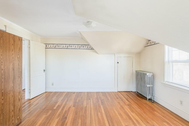 bonus room featuring vaulted ceiling, baseboards, wood finished floors, and radiator