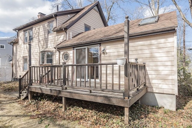 back of property featuring a shingled roof, a chimney, and a wooden deck