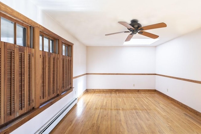 unfurnished room featuring a baseboard heating unit, plenty of natural light, baseboards, and light wood-style floors