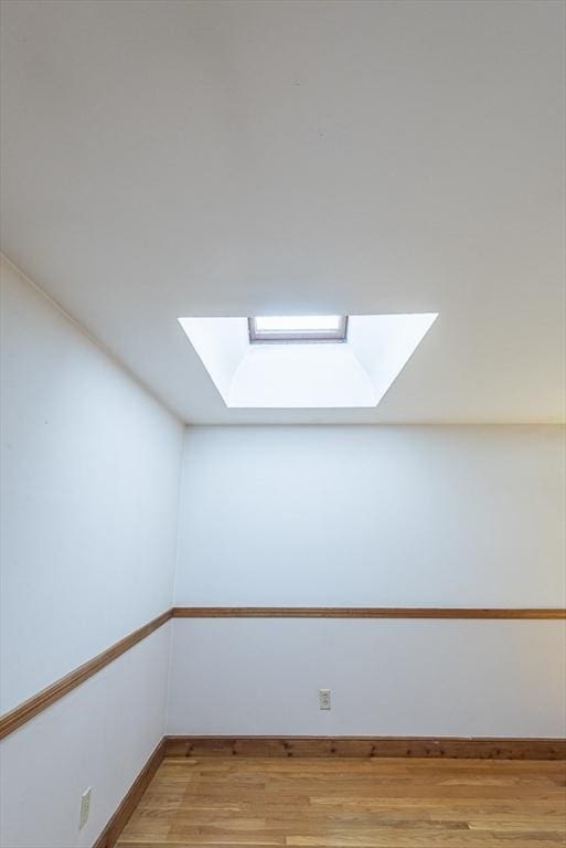 bonus room with a skylight, light wood-style flooring, and baseboards