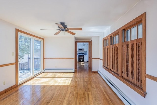 empty room featuring a baseboard radiator, baseboard heating, ceiling fan, wood finished floors, and baseboards