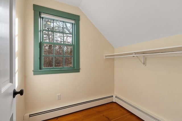 spacious closet featuring lofted ceiling, wood finished floors, and a baseboard radiator