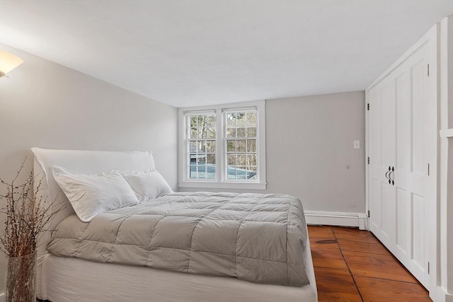 bedroom featuring a baseboard heating unit and wood finished floors