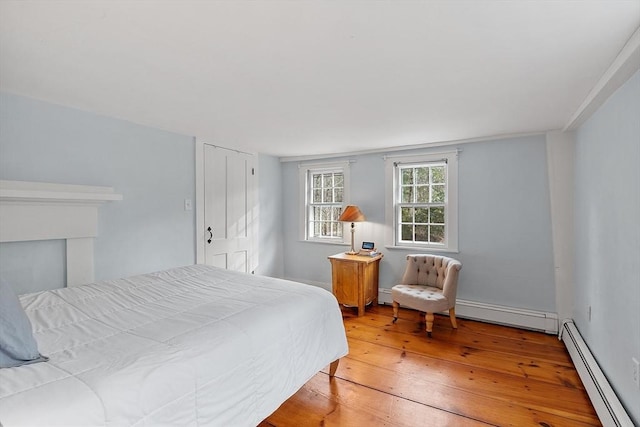 bedroom featuring a baseboard heating unit and wood-type flooring