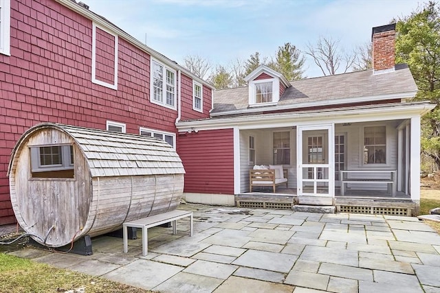 back of house featuring a patio, a sunroom, and a chimney