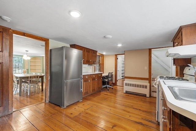 kitchen featuring white range with gas cooktop, under cabinet range hood, radiator heating unit, freestanding refrigerator, and light wood-style floors