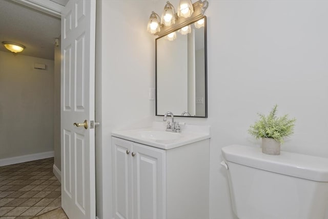 half bath with baseboards, vanity, and toilet