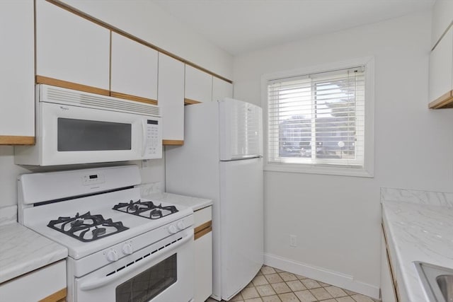 kitchen with white appliances, white cabinetry, and baseboards