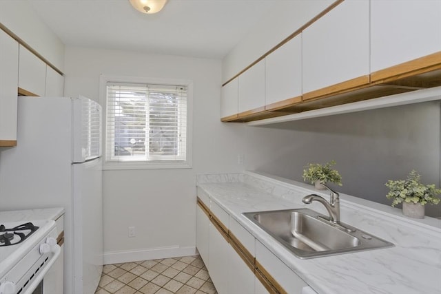 kitchen with white cabinets, a sink, light tile patterned flooring, white appliances, and baseboards