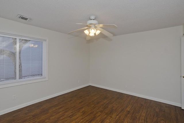 spare room featuring baseboards, a textured ceiling, visible vents, and wood finished floors