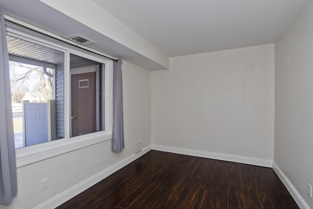 spare room featuring visible vents, dark wood finished floors, and baseboards