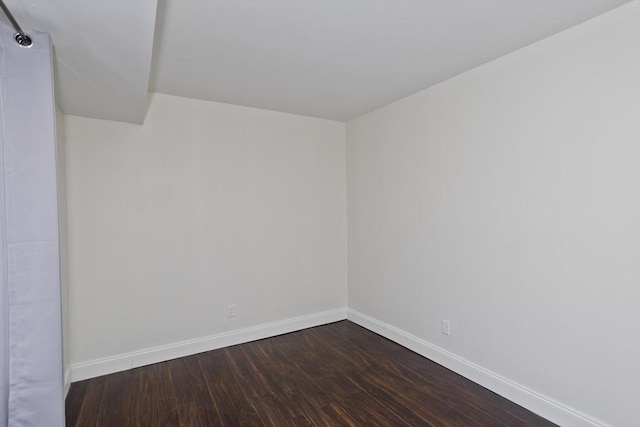 unfurnished room with baseboards and dark wood-style flooring