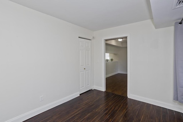 spare room featuring dark wood-style floors, visible vents, and baseboards