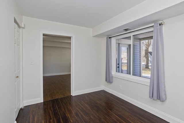 unfurnished bedroom with a closet, wood finished floors, visible vents, and baseboards