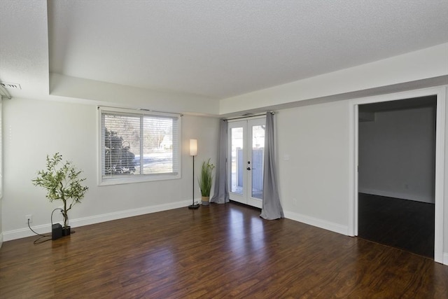 unfurnished room with a textured ceiling, french doors, wood finished floors, and baseboards