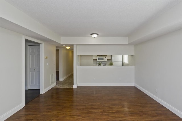 unfurnished room with baseboards, visible vents, dark wood finished floors, and a textured ceiling