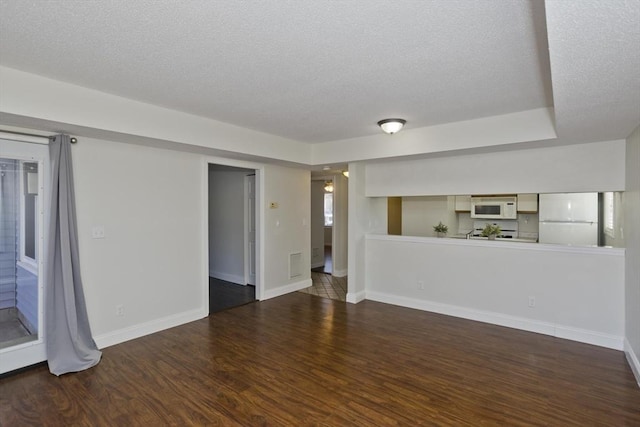 unfurnished living room with visible vents, a textured ceiling, baseboards, and wood finished floors