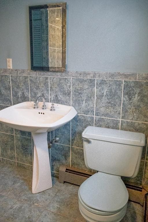 bathroom with toilet, a baseboard radiator, and tile walls