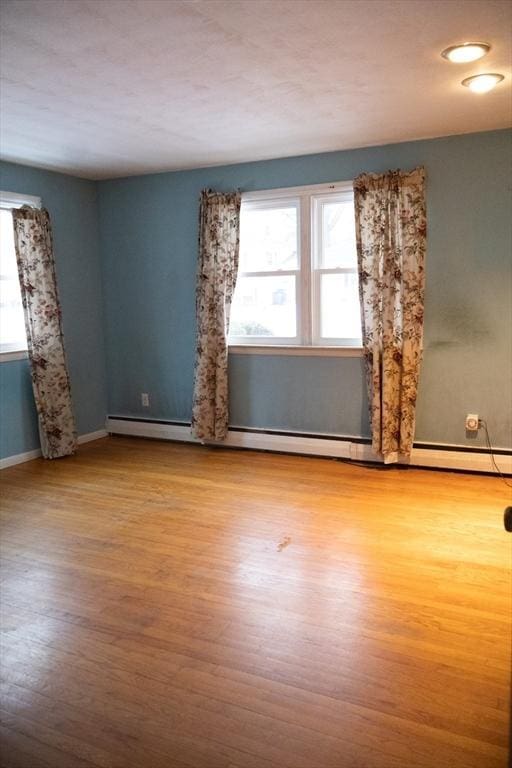 spare room featuring plenty of natural light, wood finished floors, and baseboards