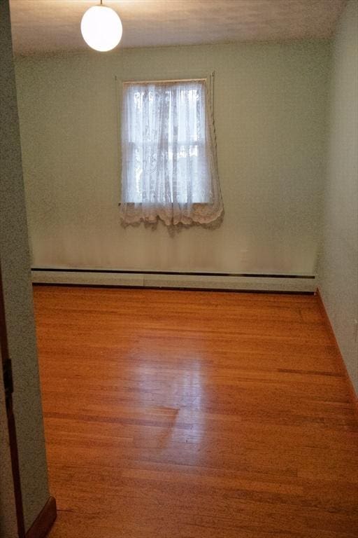 spare room with a baseboard heating unit and wood finished floors