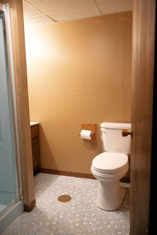 bathroom with a drop ceiling, toilet, vanity, and a shower stall