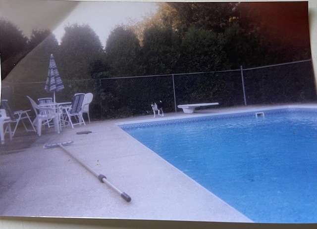 view of swimming pool featuring a patio area, fence, a diving board, and a fenced in pool