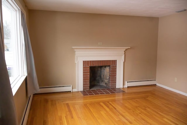 unfurnished living room featuring a baseboard radiator, a fireplace, and a wealth of natural light