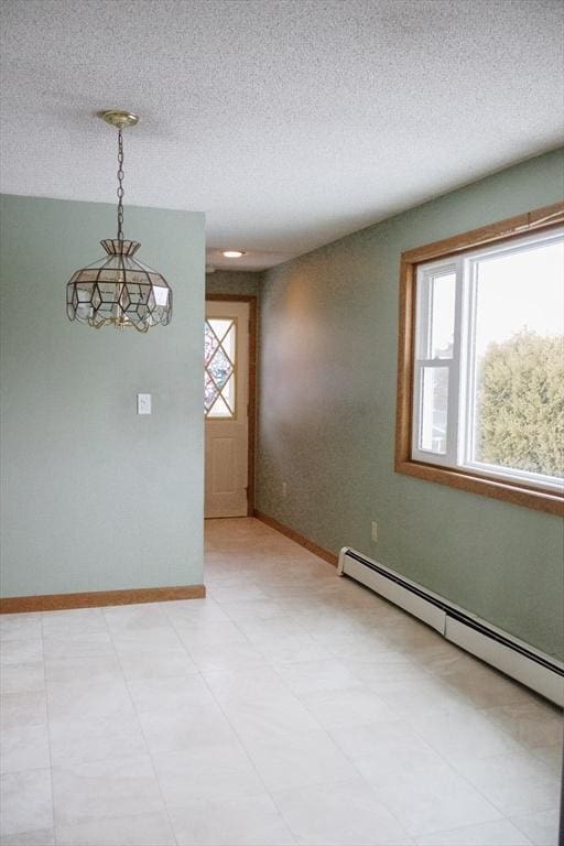 spare room with a baseboard heating unit, a textured ceiling, and baseboards