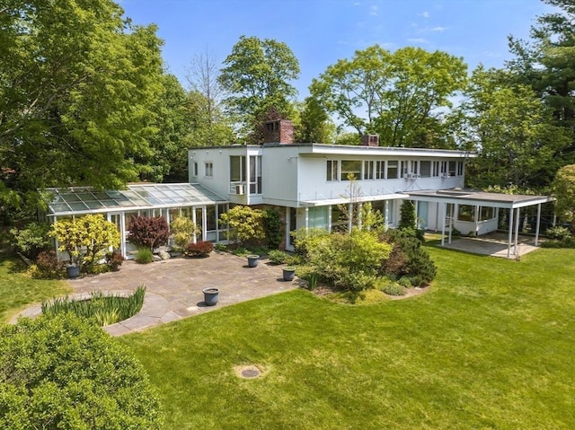 back of property featuring a patio, a lawn, and a chimney