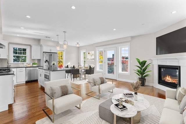 living room featuring sink, light hardwood / wood-style flooring, and a healthy amount of sunlight