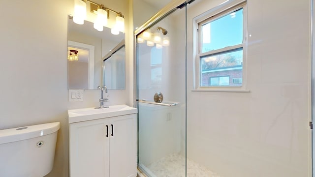 bathroom featuring vanity, toilet, and a shower with door