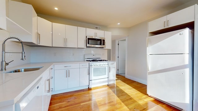 kitchen with white cabinets, white appliances, and sink