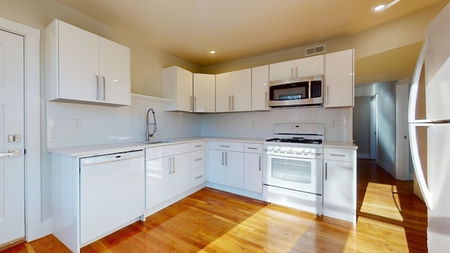 kitchen featuring white cabinets, white appliances, light hardwood / wood-style flooring, and sink