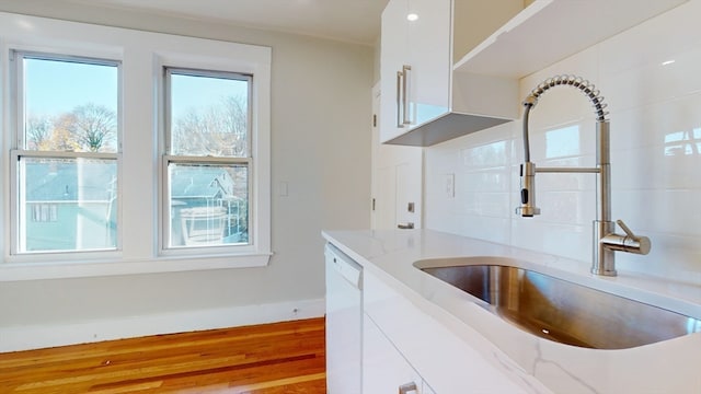 kitchen featuring white cabinets, white dishwasher, sink, light stone countertops, and light hardwood / wood-style floors