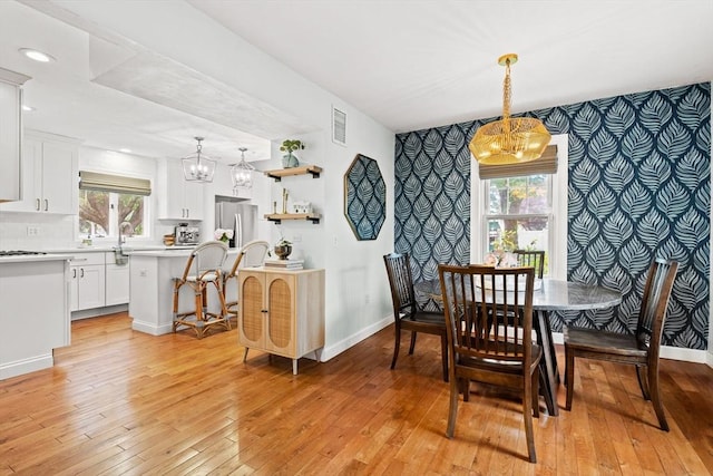 55 Rosemont Rd, Weymouth, MA 02191 - dining area with a chandelier, wallpapered walls, light wood-style floors, an accent wall, and plenty of natural light