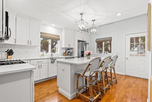 55 Rosemont Rd, Weymouth, MA 02191 - kitchen featuring stainless steel fridge with ice dispenser, backsplash, light wood finished floors, a kitchen island, and light countertops