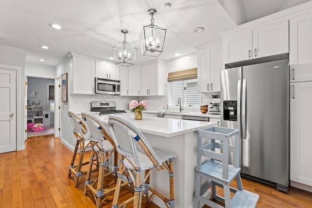 55 Rosemont Rd, Weymouth, MA 02191 - kitchen featuring stainless steel appliances, light countertops, white cabinets, a breakfast bar area, and light wood finished floors