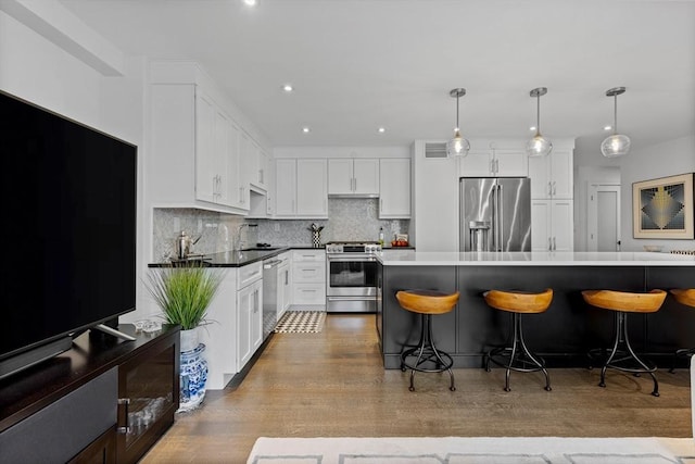 kitchen featuring a sink, appliances with stainless steel finishes, decorative backsplash, and a kitchen breakfast bar