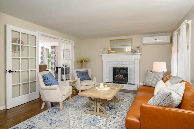 living room with an AC wall unit, wood finished floors, a fireplace, and baseboards