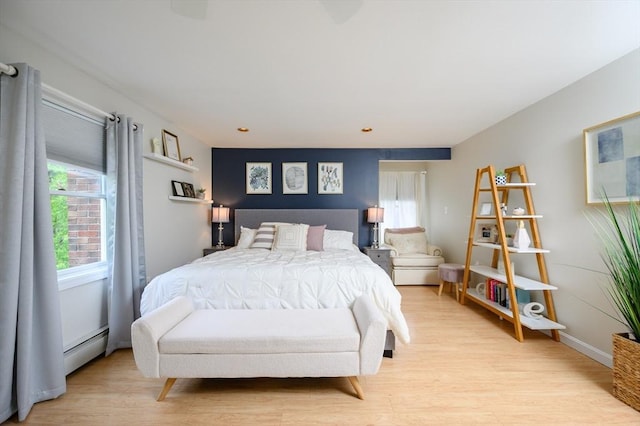 bedroom with a baseboard radiator and light wood-style flooring