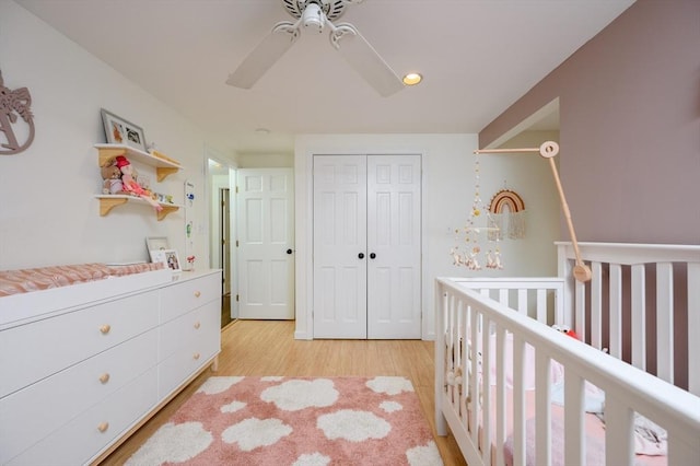bedroom featuring light wood finished floors, a closet, a nursery area, ceiling fan, and recessed lighting