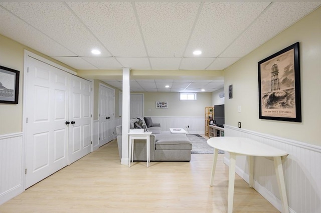 living area featuring light wood finished floors, a paneled ceiling, wainscoting, and recessed lighting